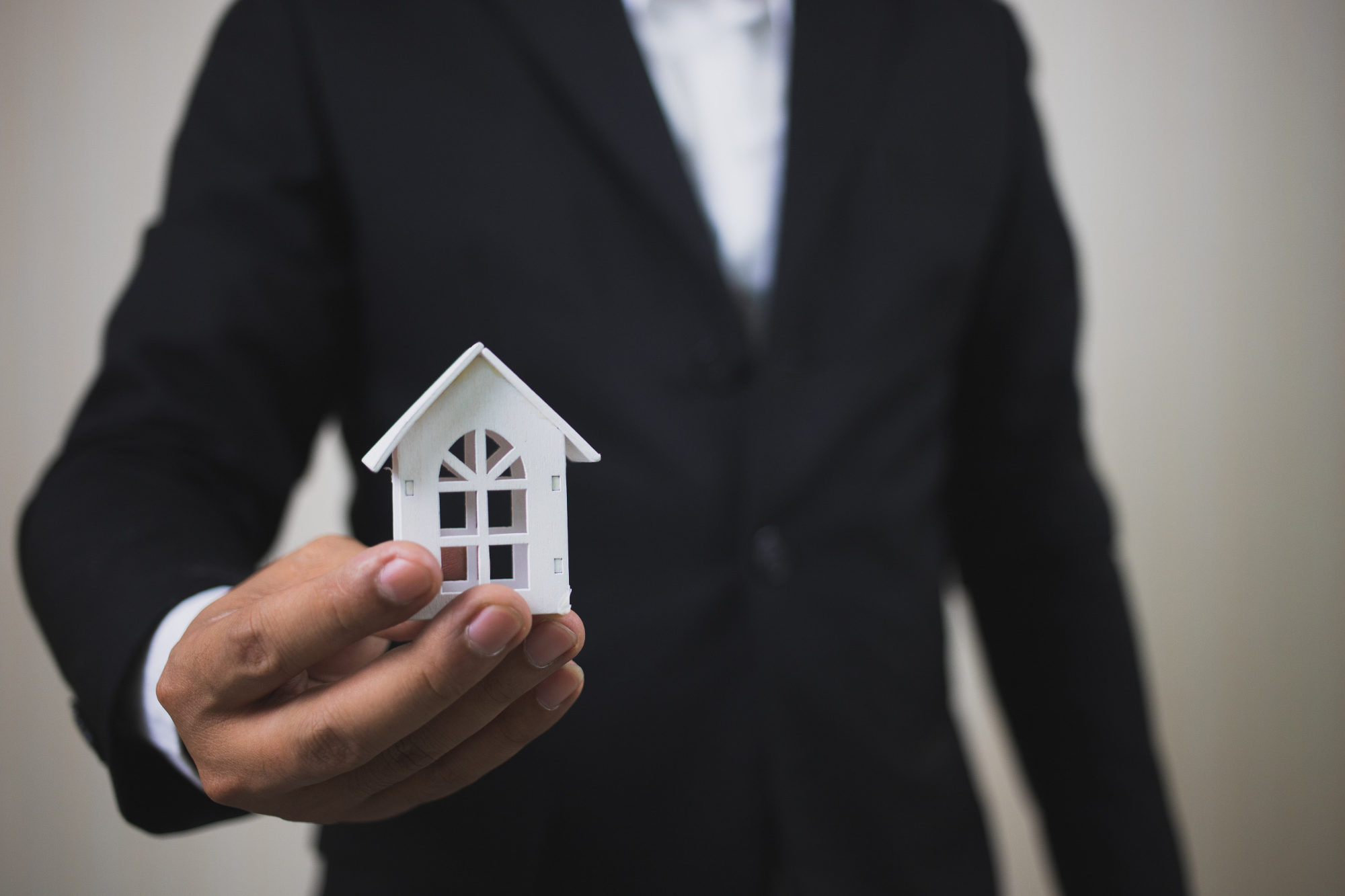 Businessman holding a white model house